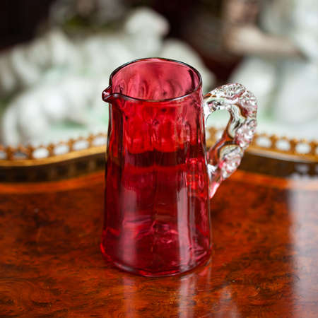 glass red mug in luxury interior. crystal cup with unusual handmade. bohemian glass closeupの写真素材