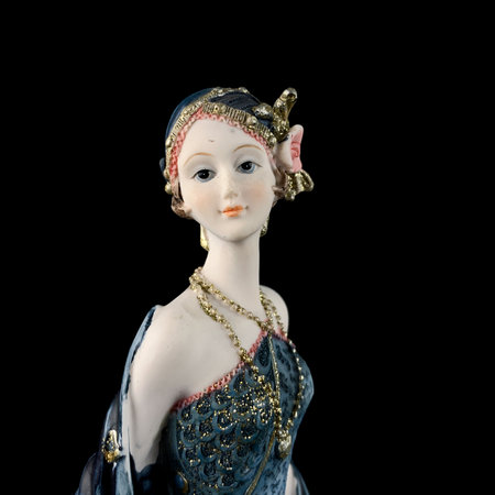 Vintage figurine of a woman in a blue dress on a black background. porcelain antique figurine of a...
