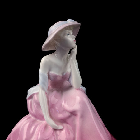 Porcelain statuette of a woman in a pink dress on a black background. antique figurine of a woman in a retro dressの写真素材