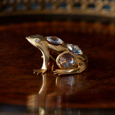 Jewelry gold ring with precious stones on a mirror background. antique gold figurine of a turtle in a luxurious interior.の写真素材