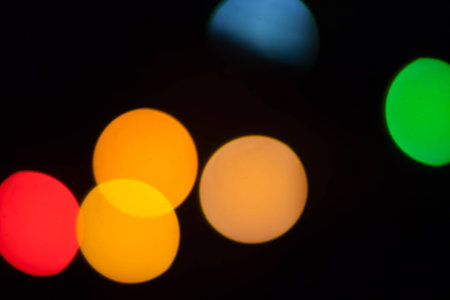Colorful abstract blurry defocused bokeh lights on black background. Green, orange and red spotsの写真素材