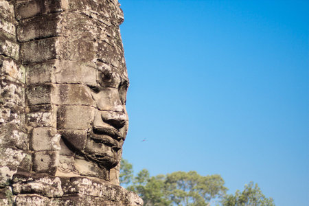 Ancient stone smiling face of the Prasat Bayon Wat temple in the jungle, Angkor wat, Cambodia. Angkor Wat isthe largest religious monument in the world.の写真素材