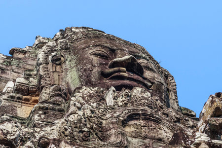 Ancient stone smiling face of the Prasat Bayon Wat temple in the jungle, Angkor wat, Cambodia. Angkor Wat isthe largest religious monument in the world.の写真素材