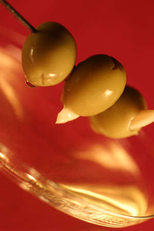 Three olives on a cocktail skewer, over a martini glass. macro, shallow DOF.の写真素材