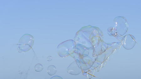 Rainbow big bubbles on the background of bright summer blue sky. Abstract soap bubble background, element for designers. Horizontalの写真素材