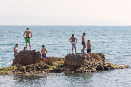 Acre, Israel - 11.05.2018: Native teenagers of city Acre resting, swimming in the Mediterranean sea. Active sports outdoor summer vacationのeditorial素材