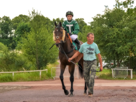 Magdeburg, Germany - 24 Juni 2017: Assistant leads the horse behind the bridle to the hippodrome. Race track in Magdeburgのeditorial素材