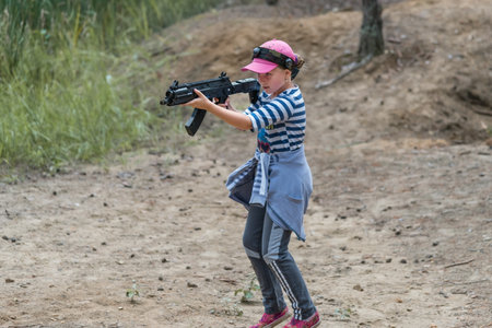 Novgorod, Russia - 04 September 2016: Girl is running and looking into the optical sight of laser tag pistol. Laser tag, a game with guns which fire infrared beams. Classmates play together outdoorsのeditorial素材