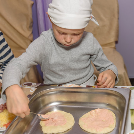 Russia, Novgorod - October 15, 2016: a small boy is cooking pizza Cooking classesのeditorial素材