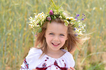 Closeup of beautiful girl wearing a wreath of wild flowers in summerの写真素材