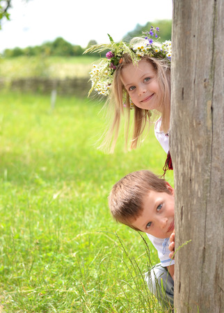 Joyful  children peeking of the tree in summerの写真素材