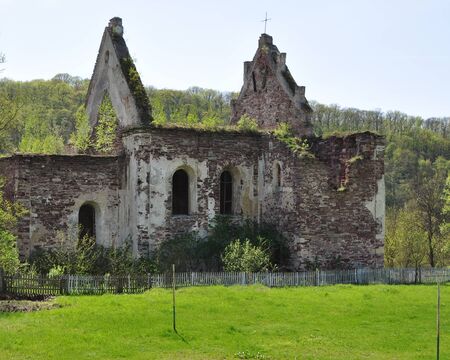An old destroyed brick building with broken arched windows. From the roof were only gables. Against...