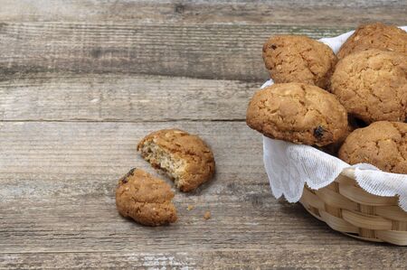 Oatmeal cookies with nuts and raisins in a wicker cracker on a white napkin. One cookie is broken...