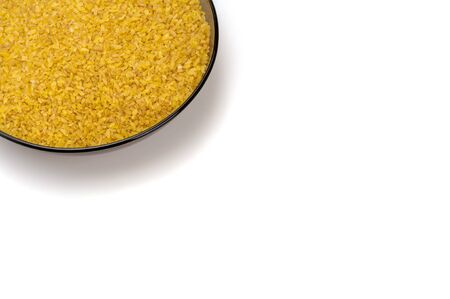 Bulgur in a brown glass plate on a white background. Angular arrangement, foreshortening. Groats of dried and crushed wheat treated with boiling water. Close up view, isolated.の写真素材