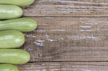 Zucchini lie on an old wooden background. Fragments of zucchini around the edge of the image. Close-up.の写真素材