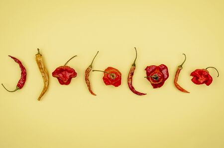 Hot red chili peppers and bell on a yellow background. Seasoning for food. Dried peppers close up view. Background mode.の写真素材