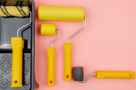 Repair wallpaper. Construction tool on a pink background. Rollers and cuvette for glue, paint.の写真素材