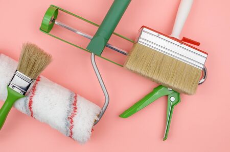 Building tool. The tool of the painter. Green objects on a pink background. Brushes and paint roller. The gun for sealant.の写真素材