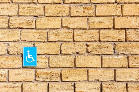 Person with disabilities sign on a stone wall. Yellow limestone masonry. Sunny day.の写真素材