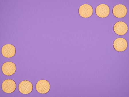 Round biscuit laid out in the corners on a purple background. The view from the top.の写真素材