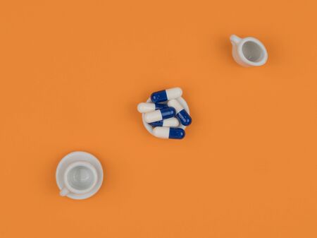 Medicine in plate on orange background. Small dishes.の写真素材