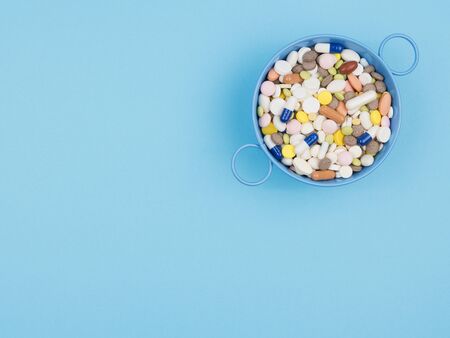 A lot of pills in the container on the blue background. The view from the top.の写真素材