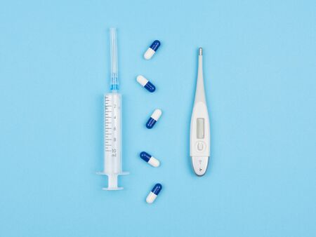 Syringe, drugs and electronic thermometer on the blue background. The view from the top. The treatment of diseases.の写真素材