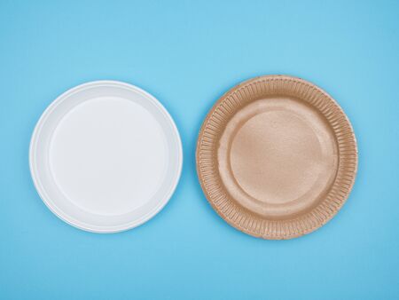 Disposable tableware on a blue background. The view from the top. Paper and plastic plates.