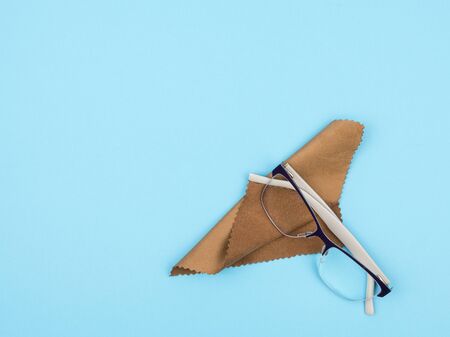 Glasses and a cloth for wiping lenses on a blue background.