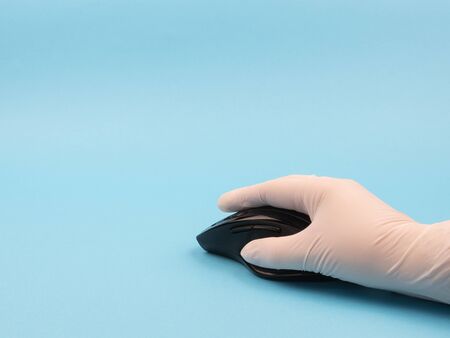 Hand in rubber glove on the mouse on a blue background. Individual means of protection. The...