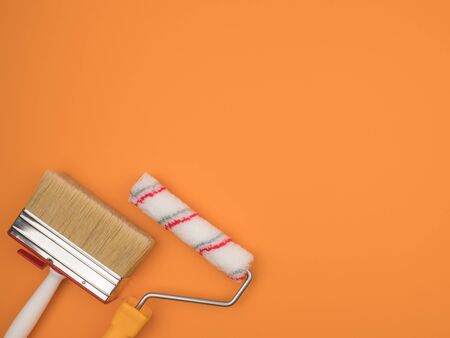 A paint roller and a large brush on an orange background. The building tool. The view from the top....