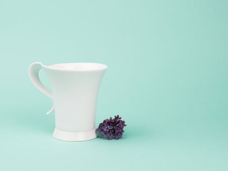 White Cup and lilacs on turquoise background.の写真素材