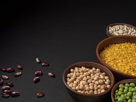 Beans in a clay pot on a black background.