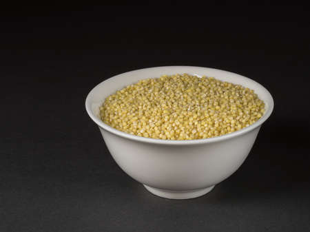 Millet in a bowl closeup on dark background.