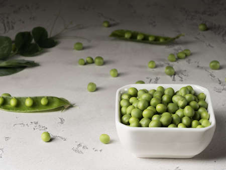 The fruits and pods of green peas on a gray background.