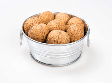 Chrome metal bowl with walnuts on a white background.の写真素材