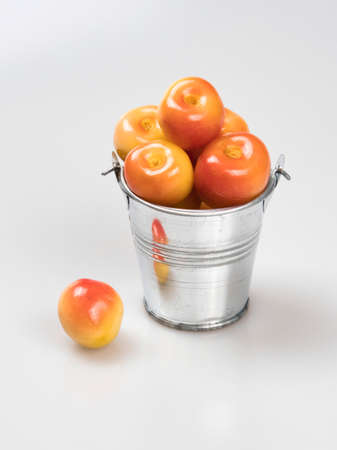 Berries of yellow cherry in a silver metal bucket and one near it. Isolated.の写真素材