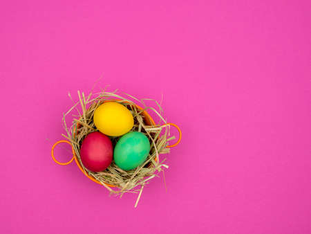 Easter eggs in a bowl on the hay. Bright pink background.の写真素材
