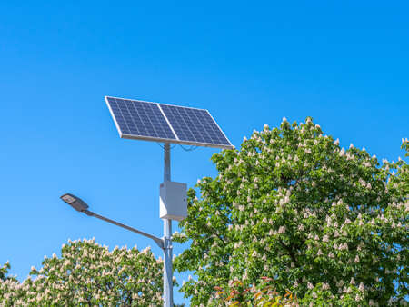 A street lamp and a solar panel against a blue sky.