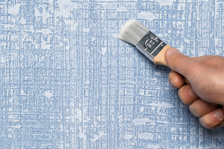 HandPainting a Beautifully Textured Blue Wallpaper Using a Brush for Adding Charmの写真素材