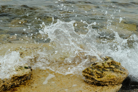 The Ocean Waves Are Splashing Vigorously on the Rocky Shoreline, Creating a Serene Atmosphereの写真素材