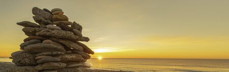 Stack of pebbles on a beach at sunset, Zen atmosphere.の写真素材
