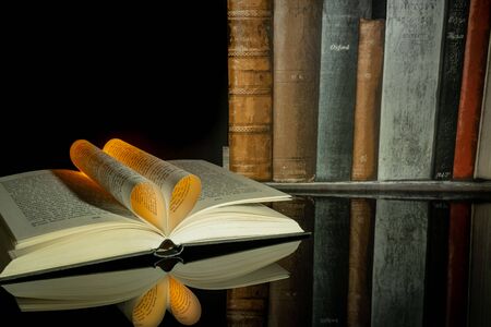 Book folded in the shape of a heart on a black background.