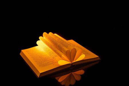 Book folded in the shape of a heart on a black background.の写真素材