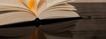 Book folded in the shape of a heart on a wooden background.の写真素材