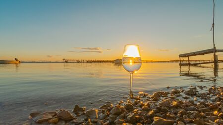 Wine glass with reflections of a sunset over the sea.の写真素材