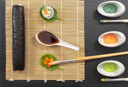 Presentation of Japanese cuisine dish, sushi and maki on black background with soy sauce and chopsticks.の写真素材