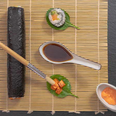 Presentation of Japanese cuisine dish, sushi and maki on black background with soy sauce and chopsticks.の写真素材