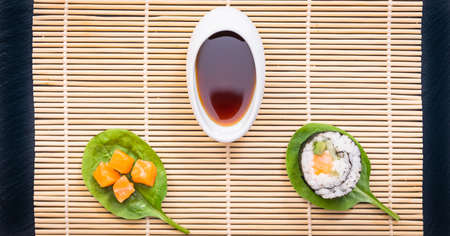 Presentation of Japanese cuisine dish, sushi and maki on black background with soy sauce and chopsticks.の写真素材