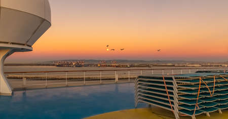View of lounge chairs on the deck of a cruise ship at sunset. View from the upper deck of the ship.の写真素材